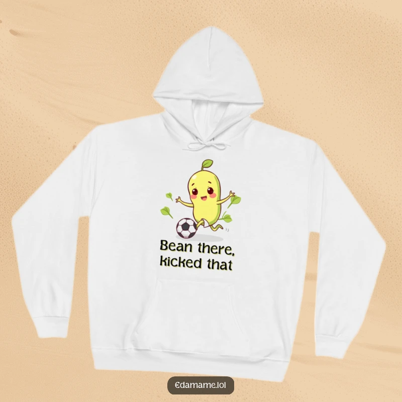 Funny hoodie design of a cheerful edamame bean in mid-kick, sending a tiny soccer ball towards the goal.